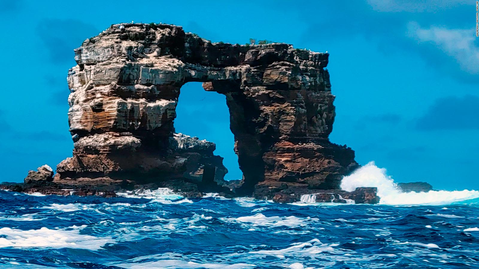 Natural sea arch and layered rock formation rising from deep blue water | Ile Tours