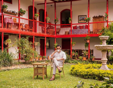 Wealthy couple relaxing on the terrace of a historic luxury coffee hacienda overlooking the lush green Andean mountains | Ile Tours