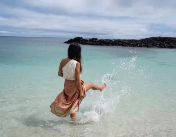 Persona en aguas turquesa junto a formaciones rocosas en Galapagos | Ile Tours
