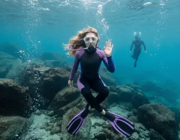 Two scuba divers underwater above rocky seabed | Ile Tours