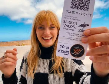 Visitor holding entry ticket with Galapagos coastal landscape and ocean horizon | Ile Tours