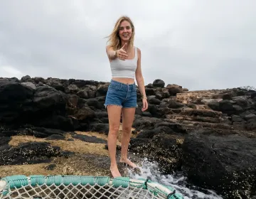 Visitor on Galapagos volcanic coastline with ocean waves and net structure | Ile Tours