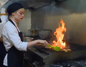 Peruvian cooking class with chef grilling meat over flames in professional kitchen | Ile Tours