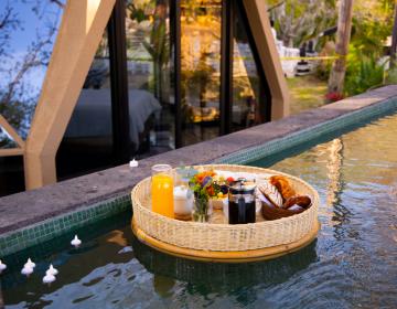 Floating breakfast setup with pastries, fruit, coffee, and juice in a luxury glamping lodge pool | Ile Tours