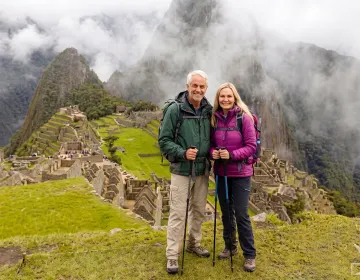 Senior travelers overlooking Machu Picchu citadel with misty mountains in background | Ile Tours