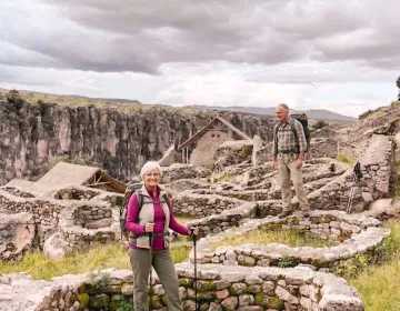 Senior travelers exploring circular Inca ruins surrounded by vegetation and cliffs | Ile Tours