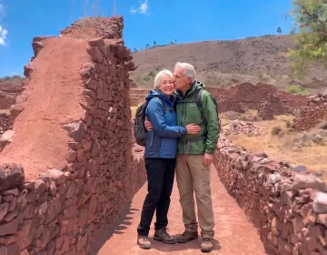 Senior travelers exploring red stone ruins with backpacks and hiking gear | Ile Tours
