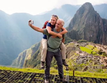 Senior travelers enjoying Machu Picchu with Huayna Picchu peak and terraces in background | Ile Tours
