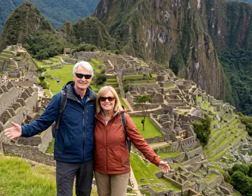 Senior travelers on slope overlooking Machu Picchu citadel and Huayna Picchu peak | Ile Tours