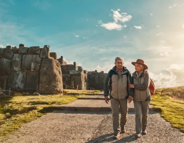 Senior travelers walking stone path at archaeological site with sunlight | Ile Tours