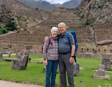 Senior travelers exploring Inca terraced ruins with backpacks and scenic mountain backdrop | Ile Tours