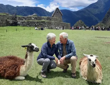 Senior travelers interacting with llamas at Machu Picchu terraces and ruins | Ile Tours