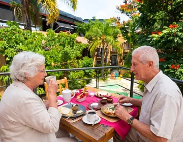 Senior couple having breakfast on a private terrace overlooking a boutique hotel garden and pool in Mexico | Ile Tours