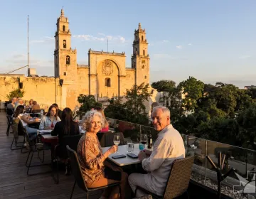 Senior couple relaxing on luxury rooftop terrace with panoramic view of San Miguel de Allende cathedral and colonial architecture | Ile Tours