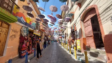 Experience the Colorful Streets of Local Markets with Ile Tours Vibrant street lined with shops and colorful hanging umbrellas, bustling with people under a bright blue sky | Ile Tours