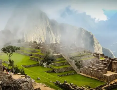 Enigmático Machu Picchu envuelto en niebla, mostrando antiguas ruinas y vegetación exuberante | Ile Tours