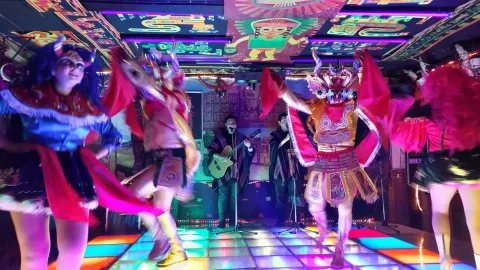 Experience the Rich Culture of Bolivian Dance | Ile Tours A lively traditional dance performance in a vibrant venue, featuring dancers in colorful costumes and musicians playing instruments. | Ile Tours