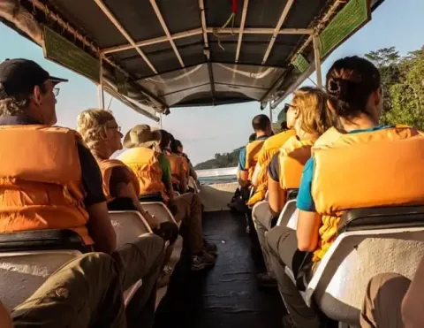 Passageiros com coletes salva-vidas sentados dentro de um barco, desfrutando de um passeio pelo rio | Ile Tours