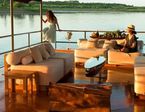 Um luxuoso interior de barco com assentos confortáveis, com dois hóspedes aproveitando a vista cênica do rio | Ile Tours