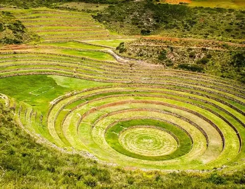 A stunning view of the circular agricultural terraces at Moray, showcasing the unique design and vibrant green landscape, highlighting the ingenuity of ancient Incan agriculture | Ile Tours
