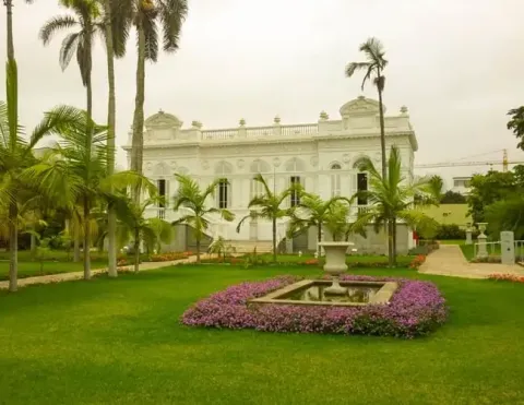 Um impressionante edifício colonial cercado por palmeiras e flores vibrantes em um jardim exuberante | Ile Tours