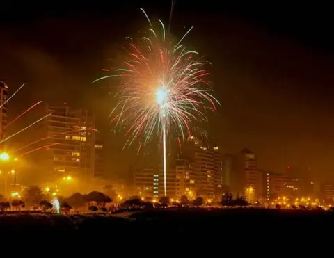 Un impresionante espectáculo de fuegos artificiales iluminando el cielo nocturno sobre un paisaje urbano vibrante, con edificios brillando en el fondo y creando una atmósfera festiva | Ile Tours