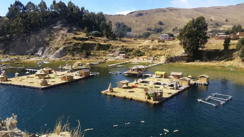 Ilhas flutuantes tradicionais dos Uros no Lago Titicaca, mostrando casas de junco e a vibrante vida comunitária com as montanhas andinas ao fundo no Peru | Ile Tours