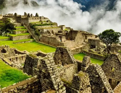 A stunning view of the ancient Inca city of Machu Picchu, nestled in the mountains with clouds overhead.