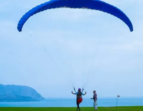 A paraglider preparing for takeoff on the scenic cliffs of Lima, Peru, with the ocean in the background and a stunning coastal view | Ile Tours