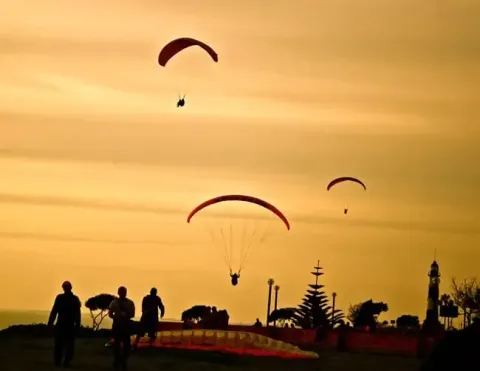 Paragliders flying over the coast at sunset in Miraflores, Lima, Peru.