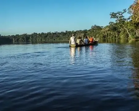 Um grupo de pessoas em uma canoa em um rio calmo cercado por vegetação exuberante | Ile Tours