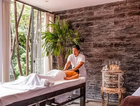 Mujer recibiendo un relajante masaje de espalda en un spa con vista a la naturaleza | Ile Tours