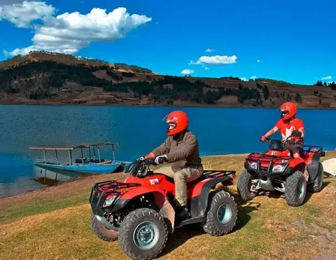 Dos personas conduciendo cuatrimotos cerca de un lago azul en los Andes | Ile Tours