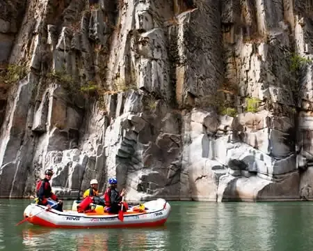 Um grupo de rafters aproveitando um momento calmo no rio, com impressionantes formações rochosas ao fundo | Ile Tours