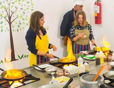 A close-up of hands using a traditional stone mortar (batan) to grind fresh ingredients during a Peruvian cooking class in Cusco, showcasing authentic culinary techniques | Ile Tours