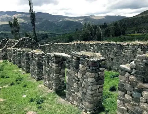 Stone structures at Uyo Uyo ruins with green hills in background | Ile Tours